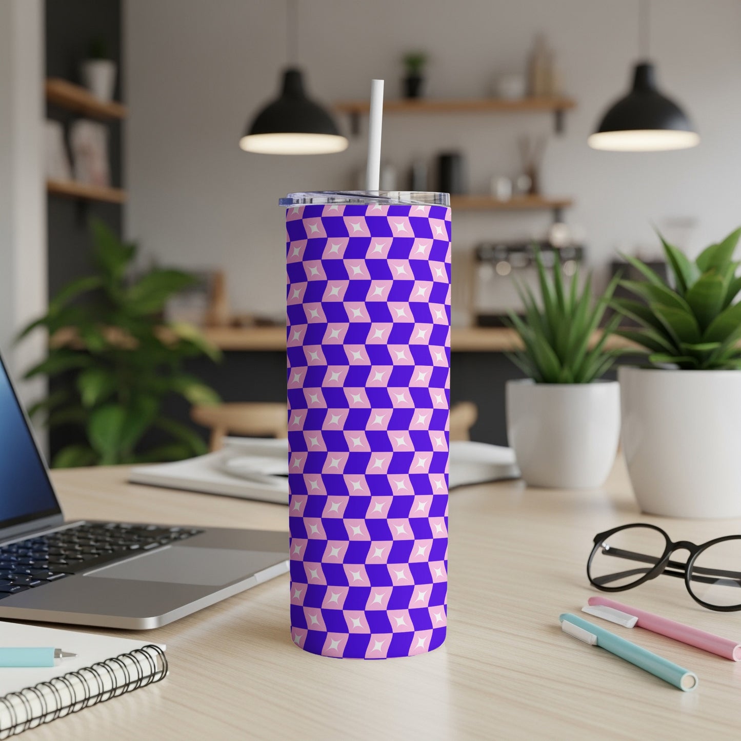 Purple and pink geometric pattern tumbler with straw on a desk.
