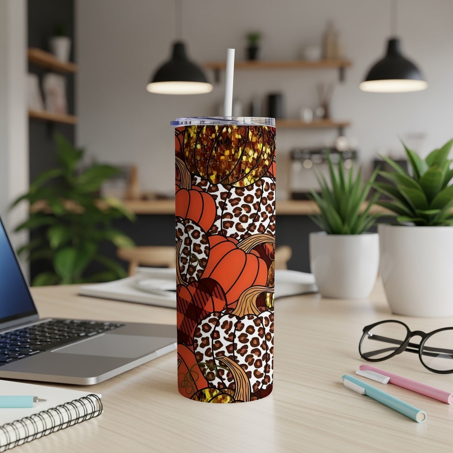 Tumbler with pumpkins and leopard print pattern on a desk.
