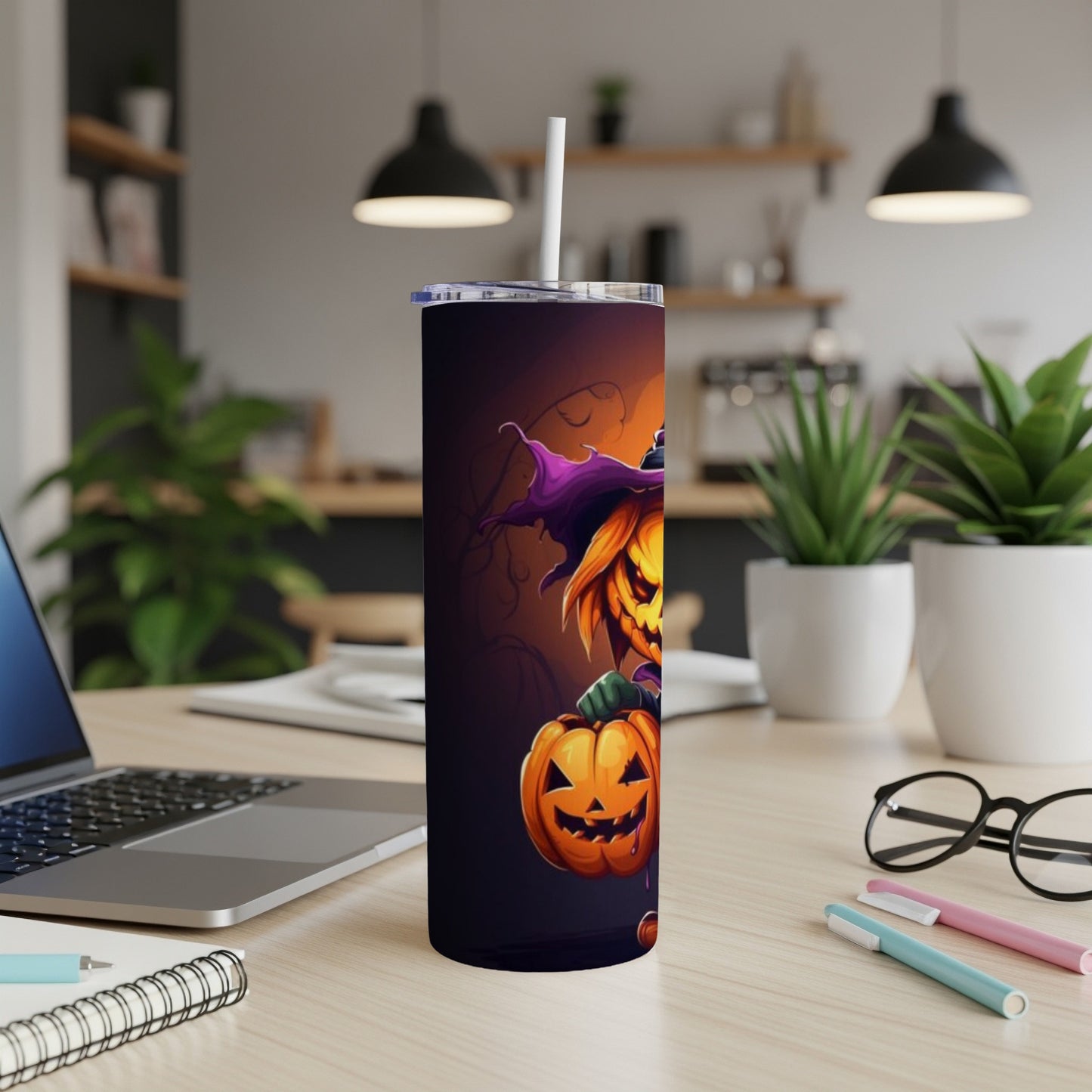 Tumbler with a cartoon witch and pumpkin design on a desk.