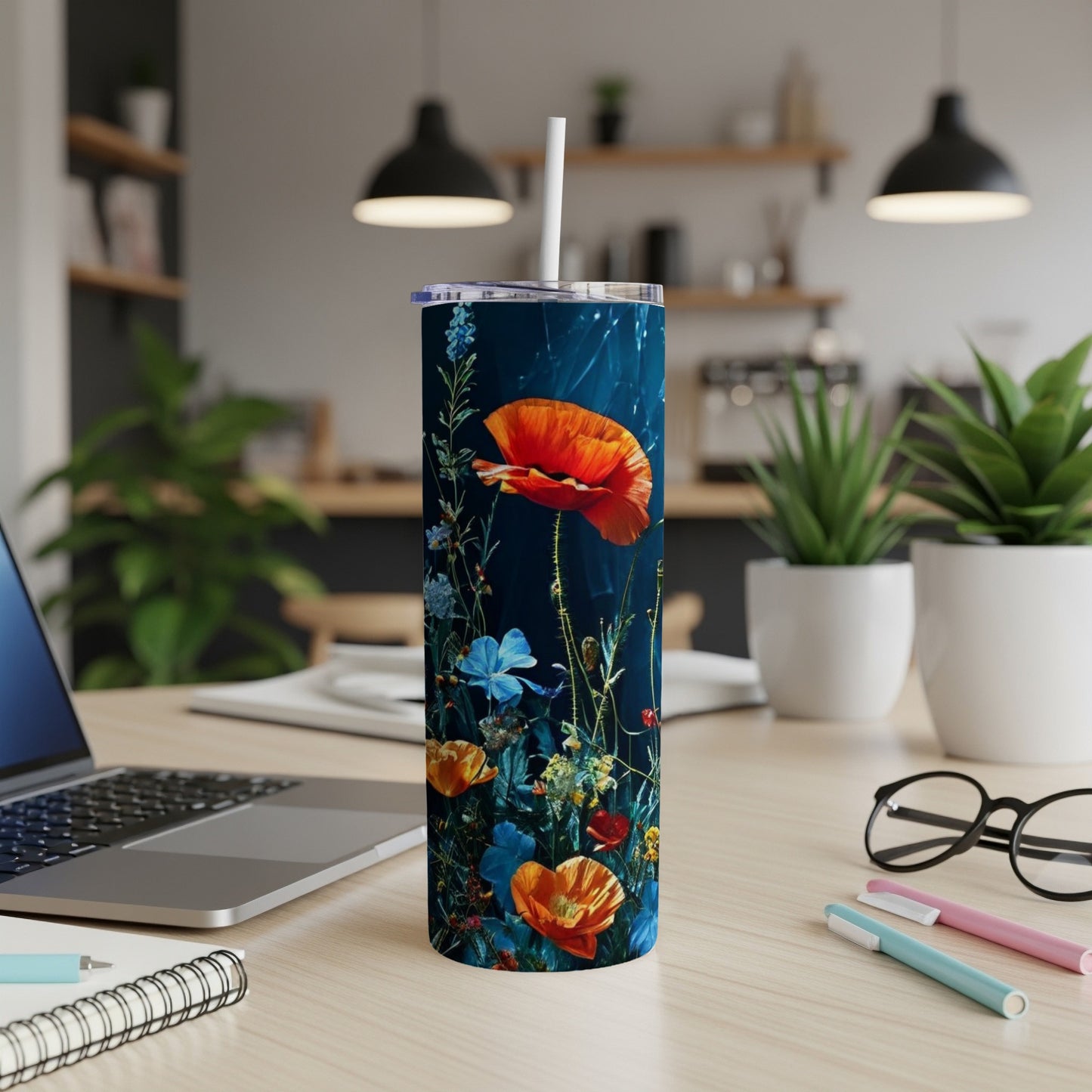 Floral pattern tumbler with poppies, blue flowers, and greenery on a desk.