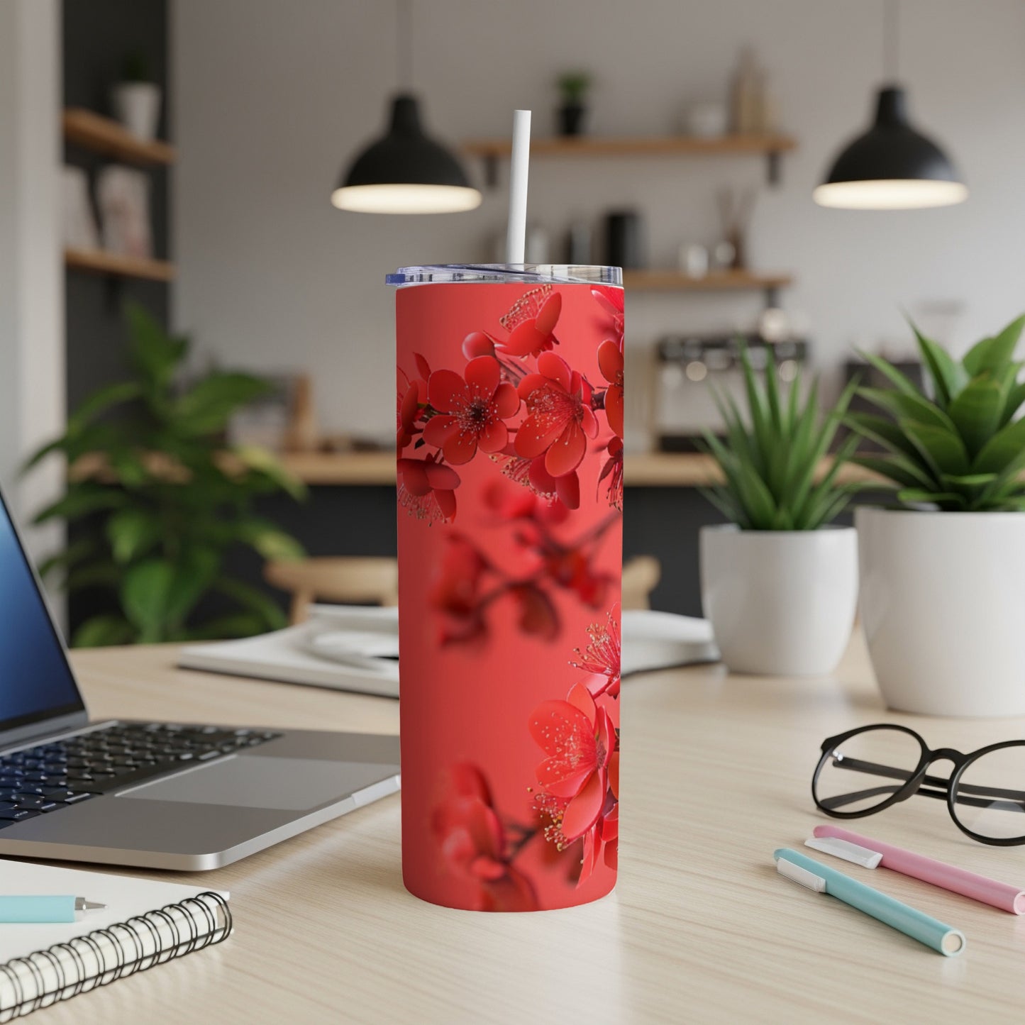 Red floral skinny tumbler with straw on a desk.