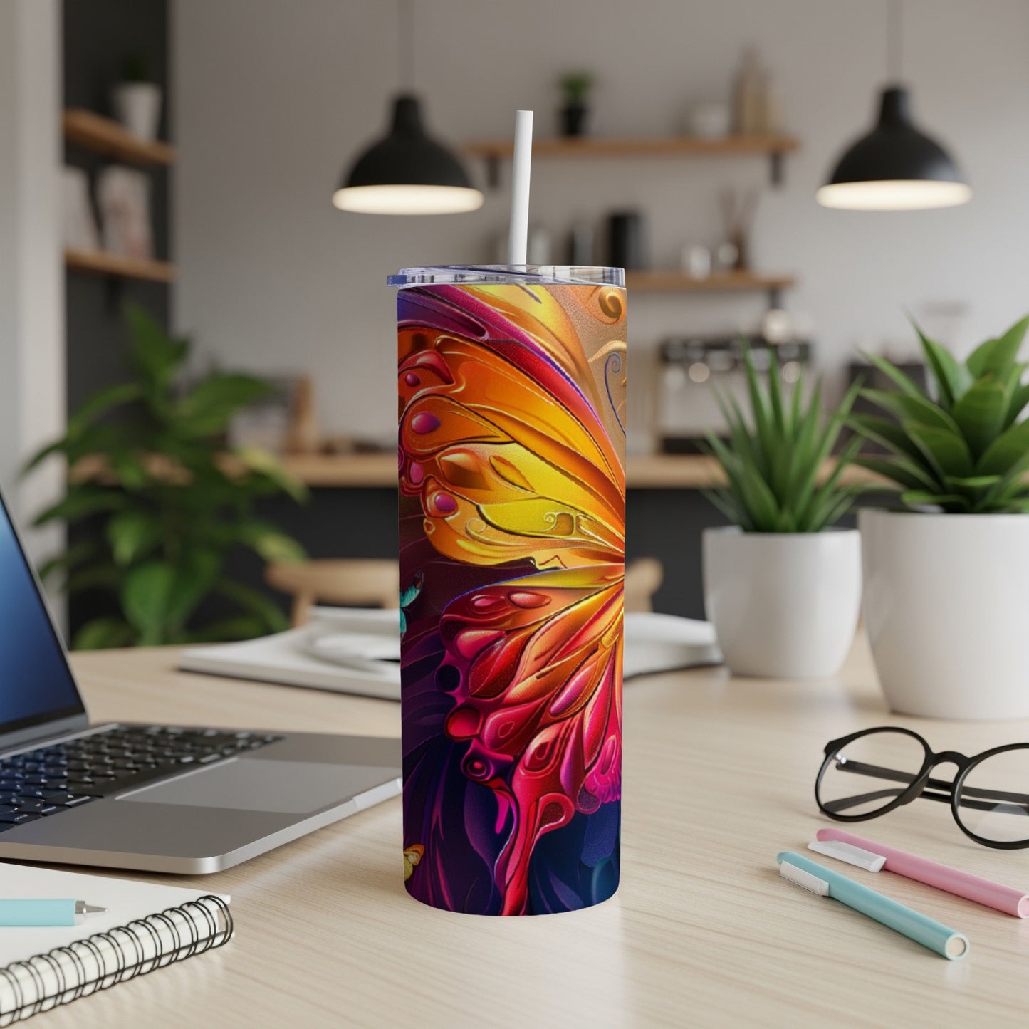 Tumbler with vibrant butterfly wing design and straw on a desk.
