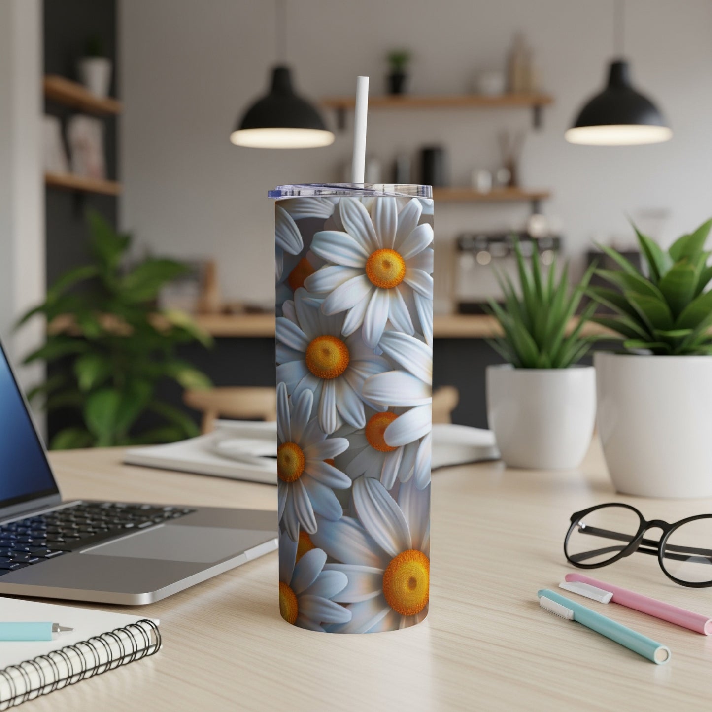White daisies cover a white skinny tumbler with a straw.