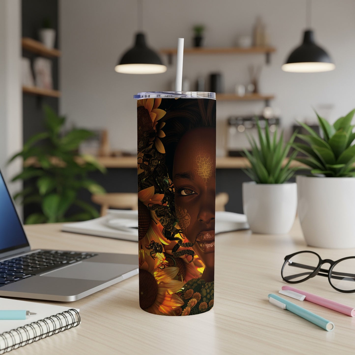 Tumbler with a woman's face and sunflowers, a straw in the lid.