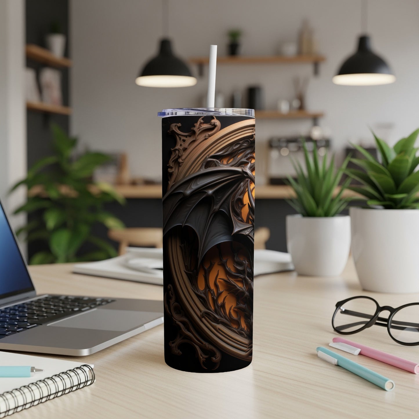 Black tumbler with dragon wings and ornate frame design, with a straw.