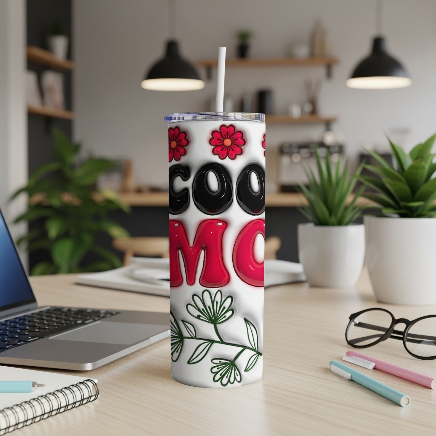 Tumbler with "Cool Mom" text and floral design on desk.