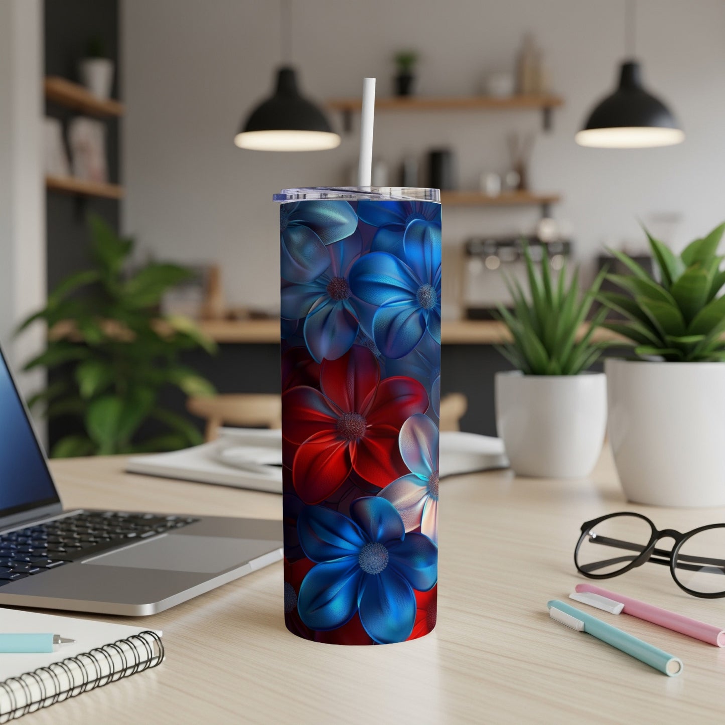 Blue and red floral tumbler with white straw on a desk.