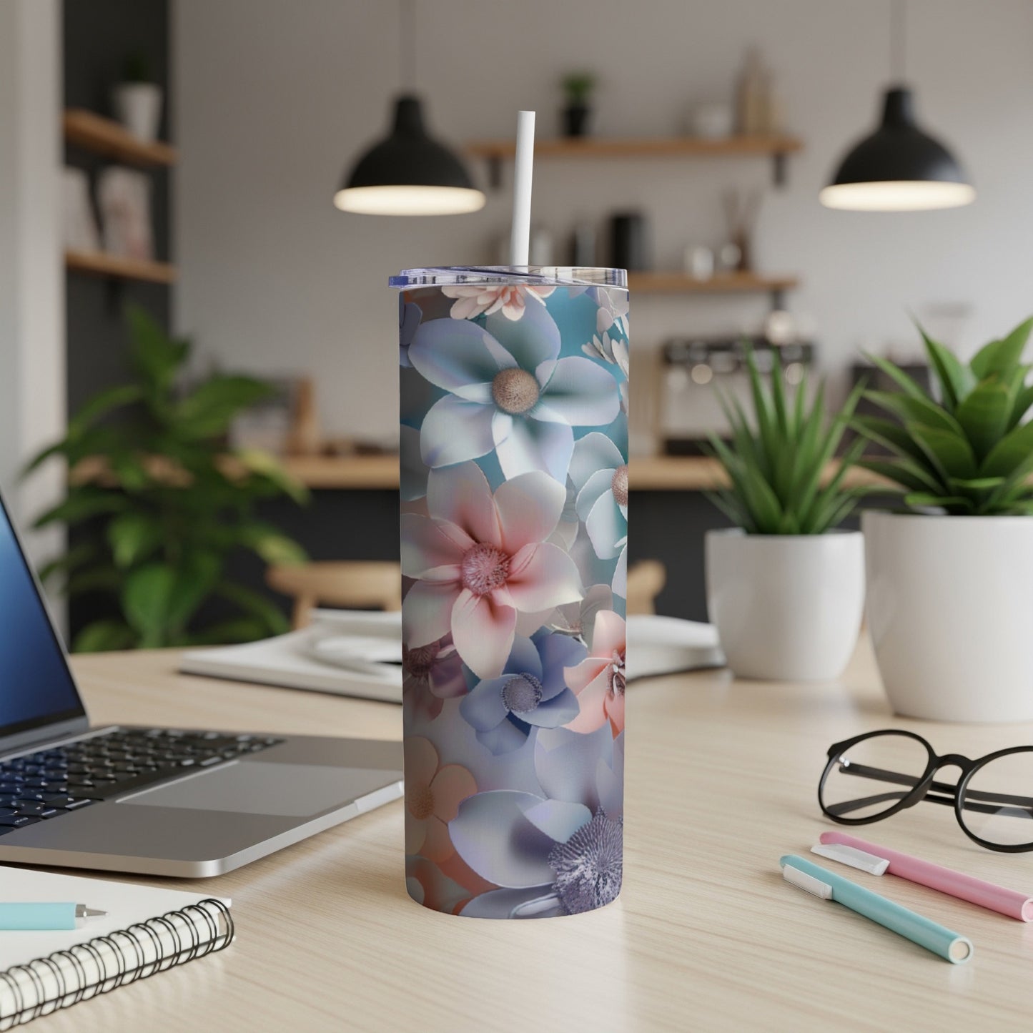 Floral patterned skinny tumbler with straw on a desk.