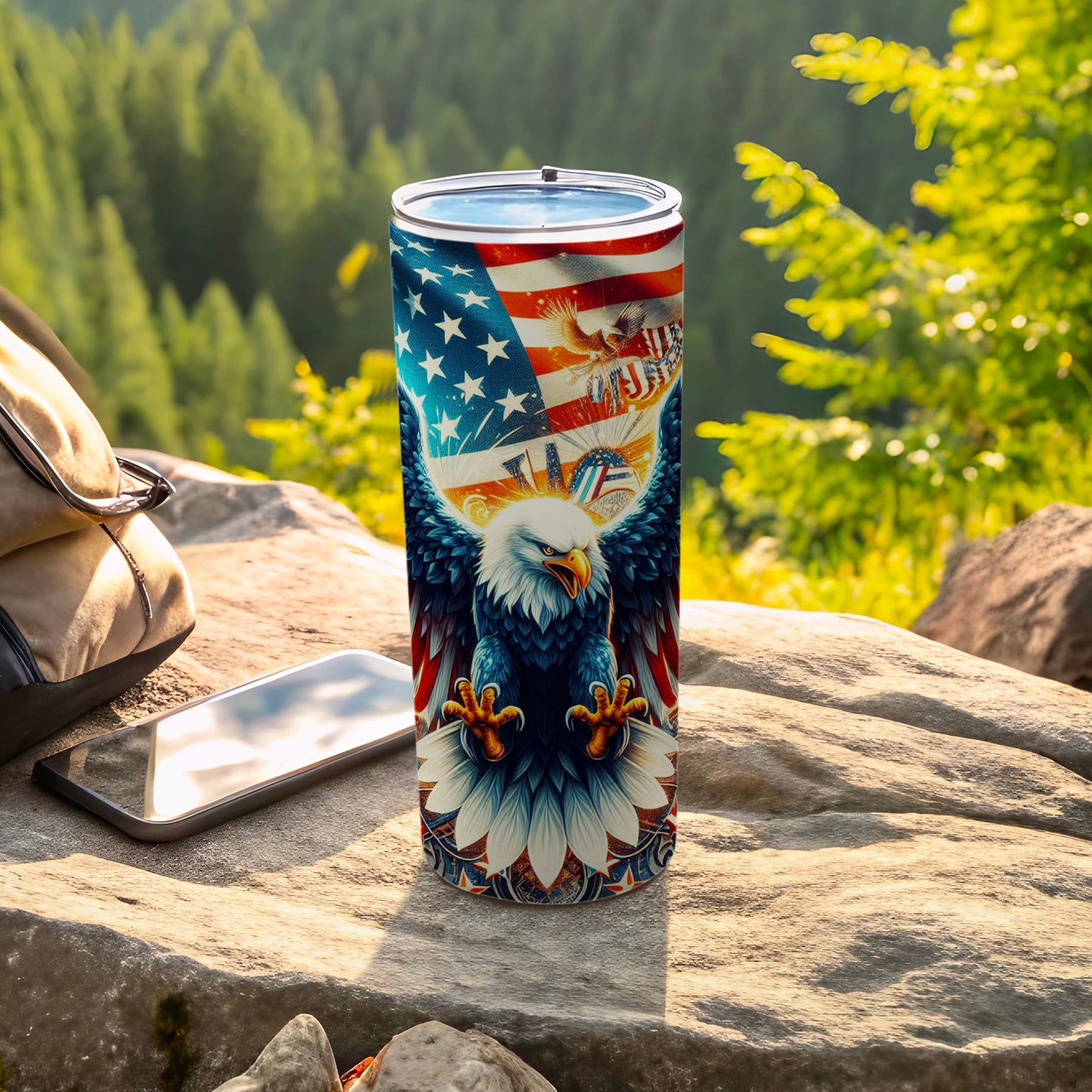 American flag eagle tumbler with a backpack and phone on rocks.