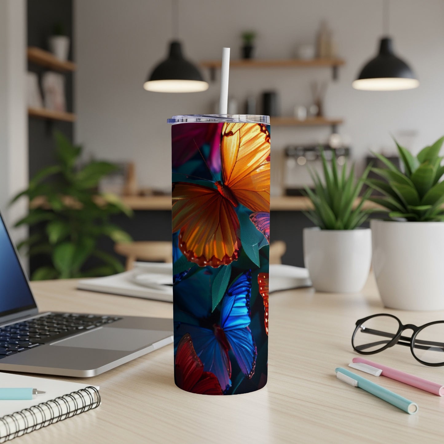 Tumbler with vibrant butterfly art, white straw, on a desk.