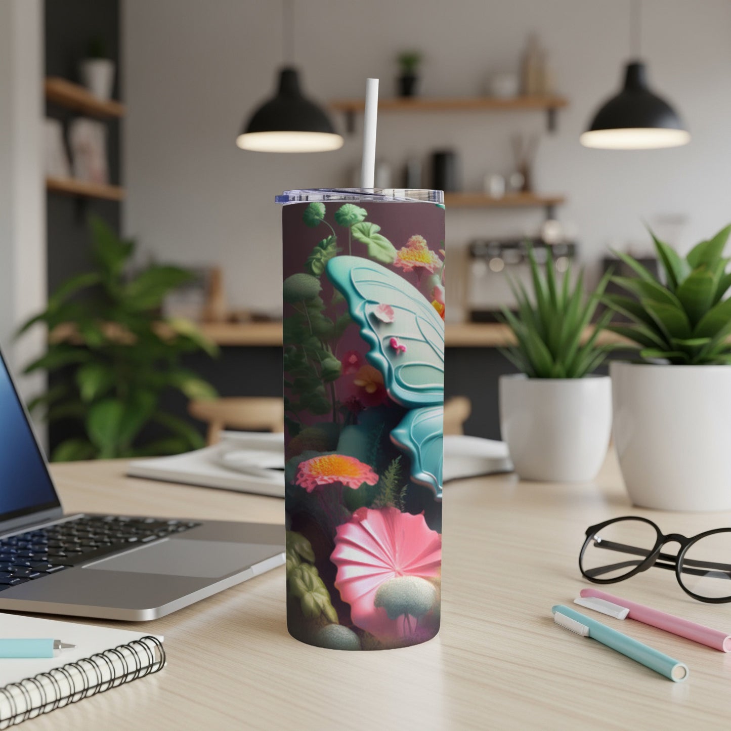 Tall tumbler with butterfly and floral design on a desk.