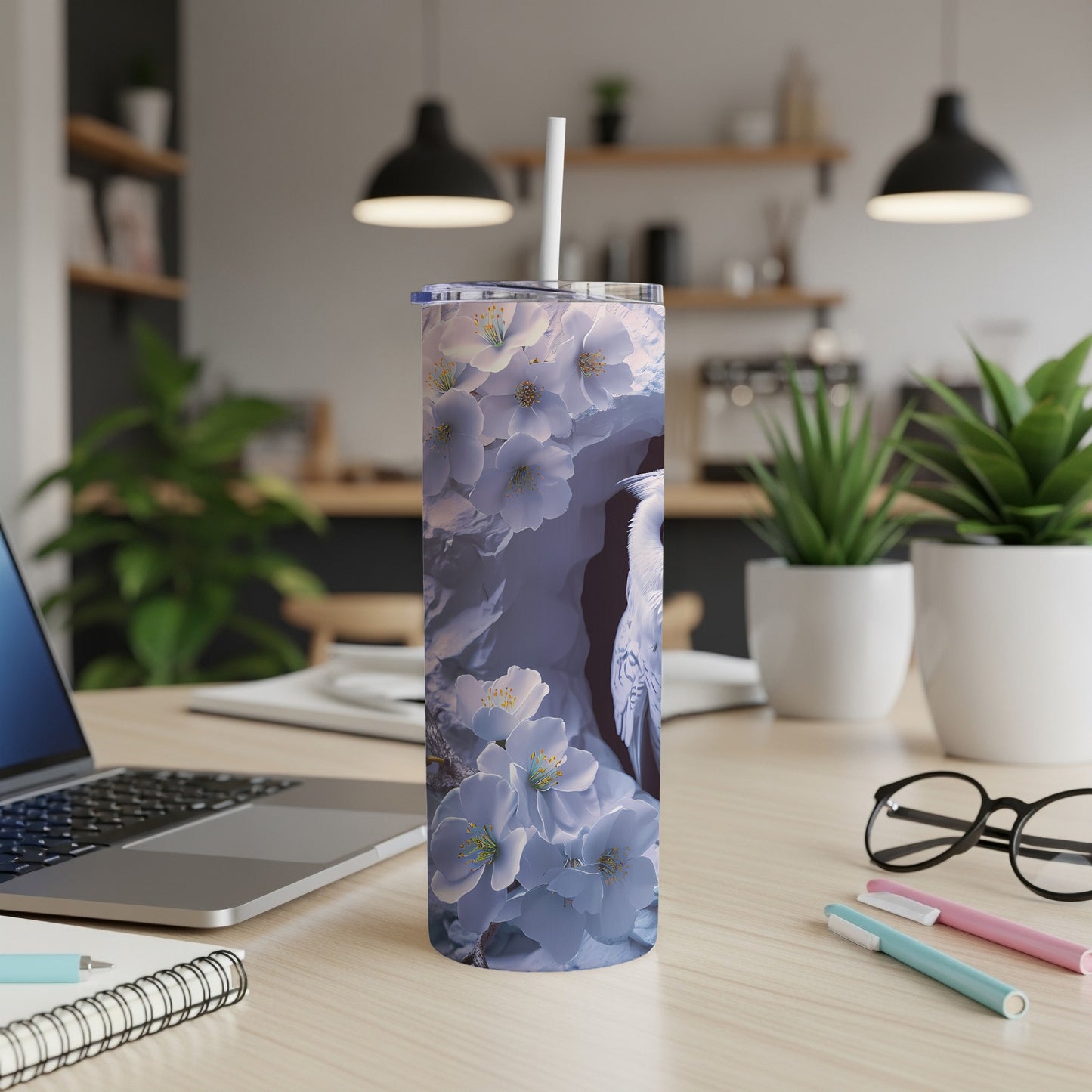 White hummingbird among pale blue cherry blossoms on a tumbler.