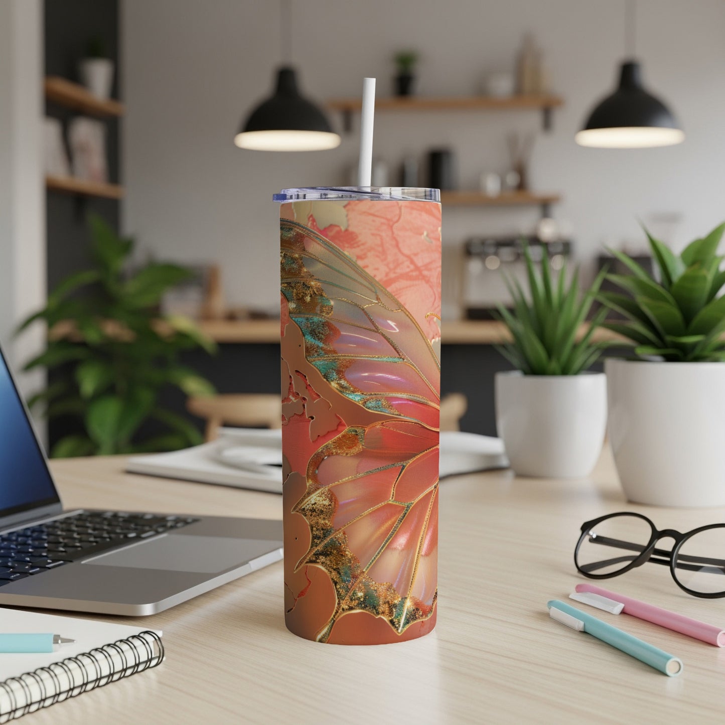 Pink and gold iridescent butterfly wing tumbler on a desk.