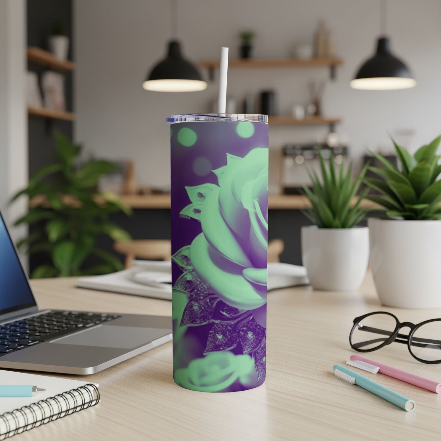 Green rose tumbler with straw on desk, laptop, and pens.