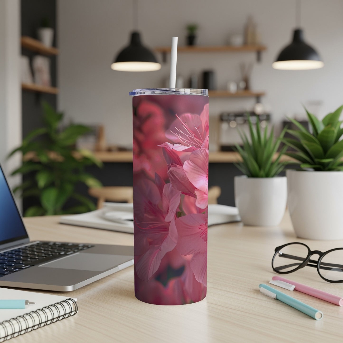 Pink azalea flowers bloom on a stainless steel tumbler with a straw.