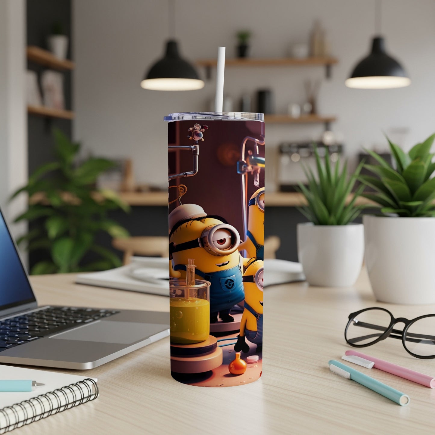 Minions characters on a tumbler with straw, next to a laptop and stationery.