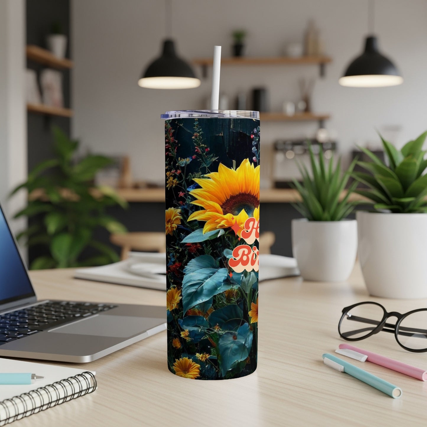Tall tumbler with sunflower and "Happy Birthday" text on desk.