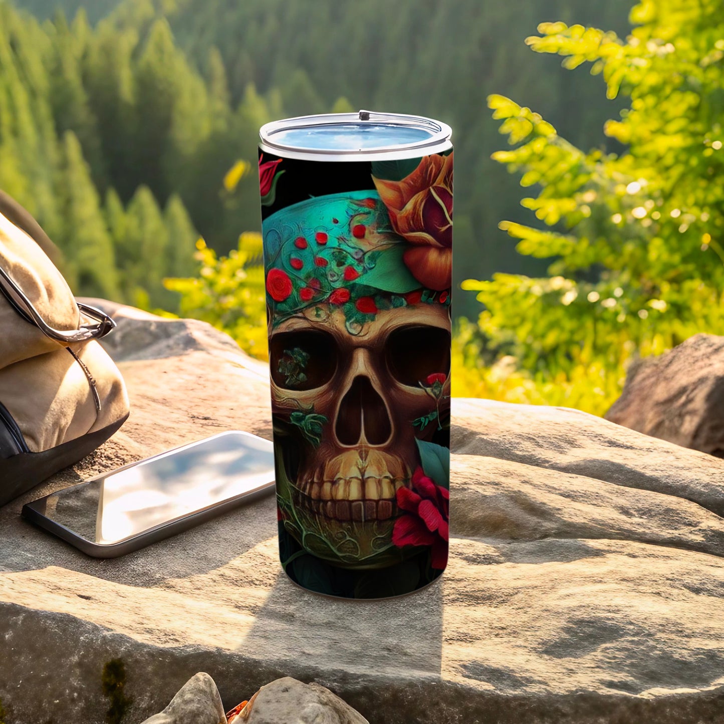Tall tumbler with skull and roses design on outdoor rocky surface.