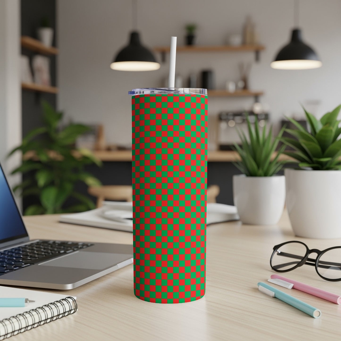 Red and green checkered tumbler with white straw on a desk.