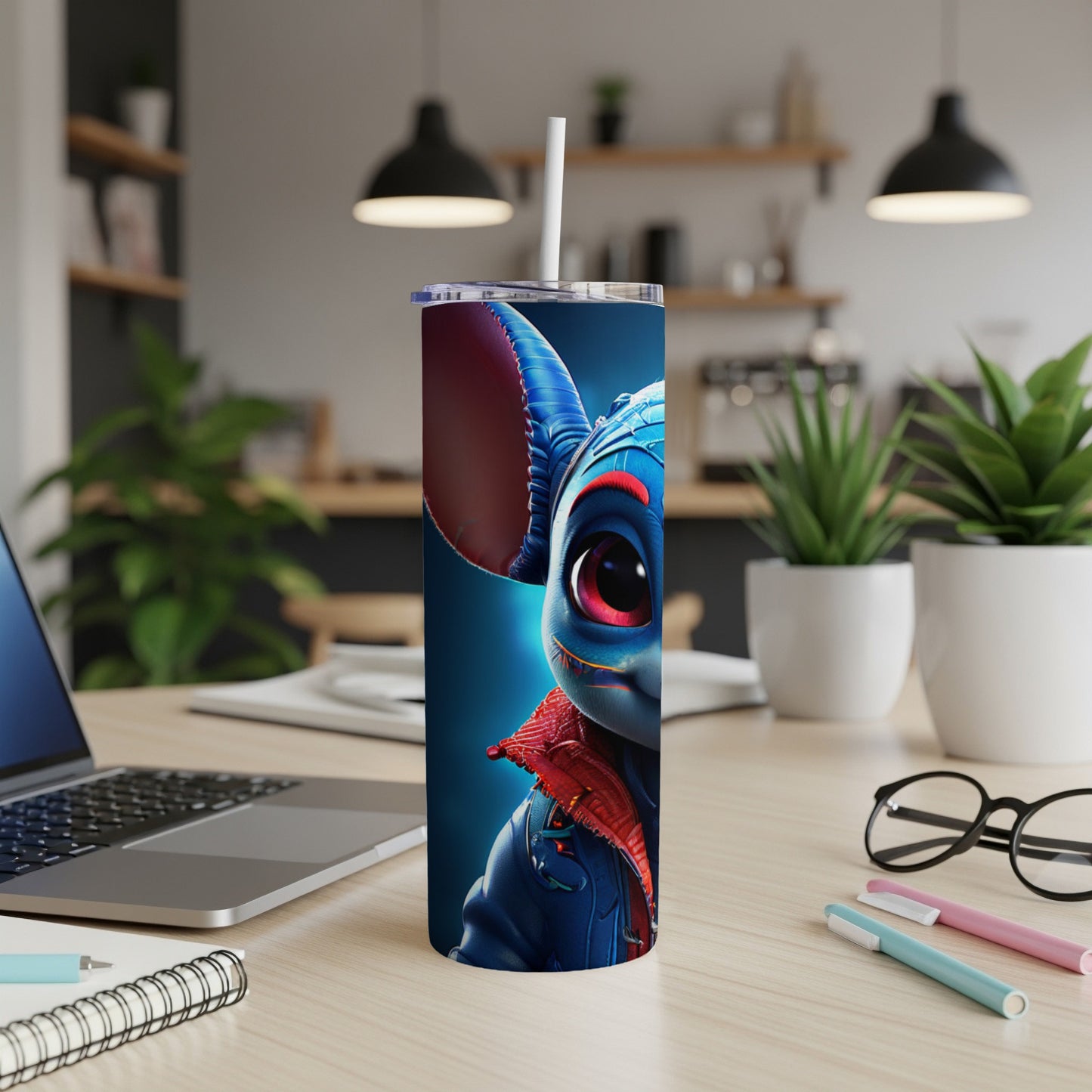 Blue creature tumbler with red eyes and jacket, on a desk.