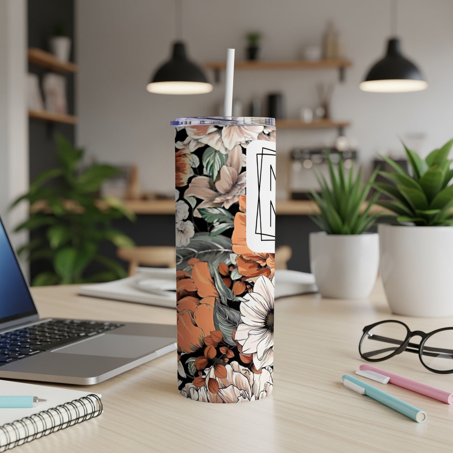 Floral tumbler with white lid and straw on desk.