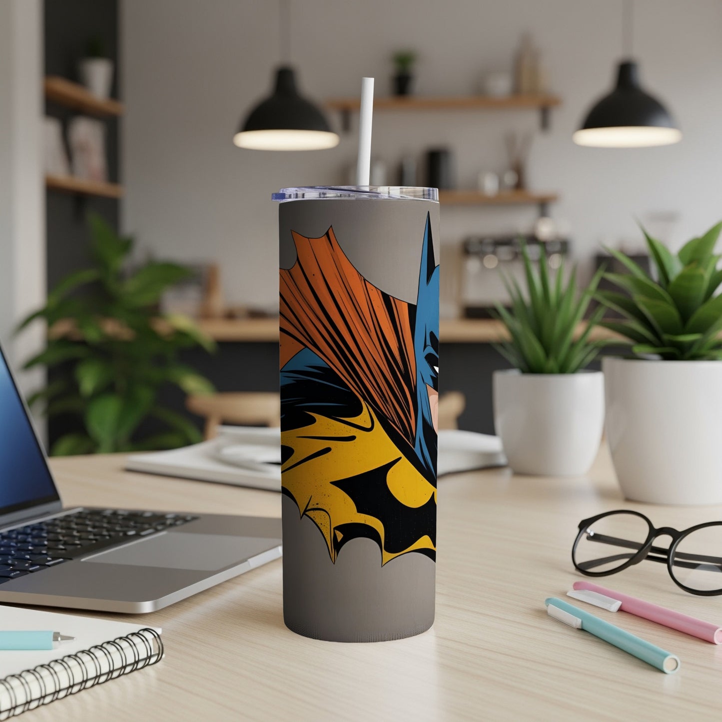 Batman illustration on a gray tumbler with a straw on a desk.