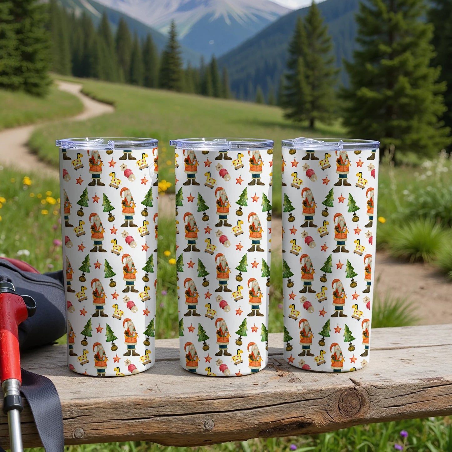 Three Santa Claus and Christmas tree patterned tumblers on a wooden surface.
