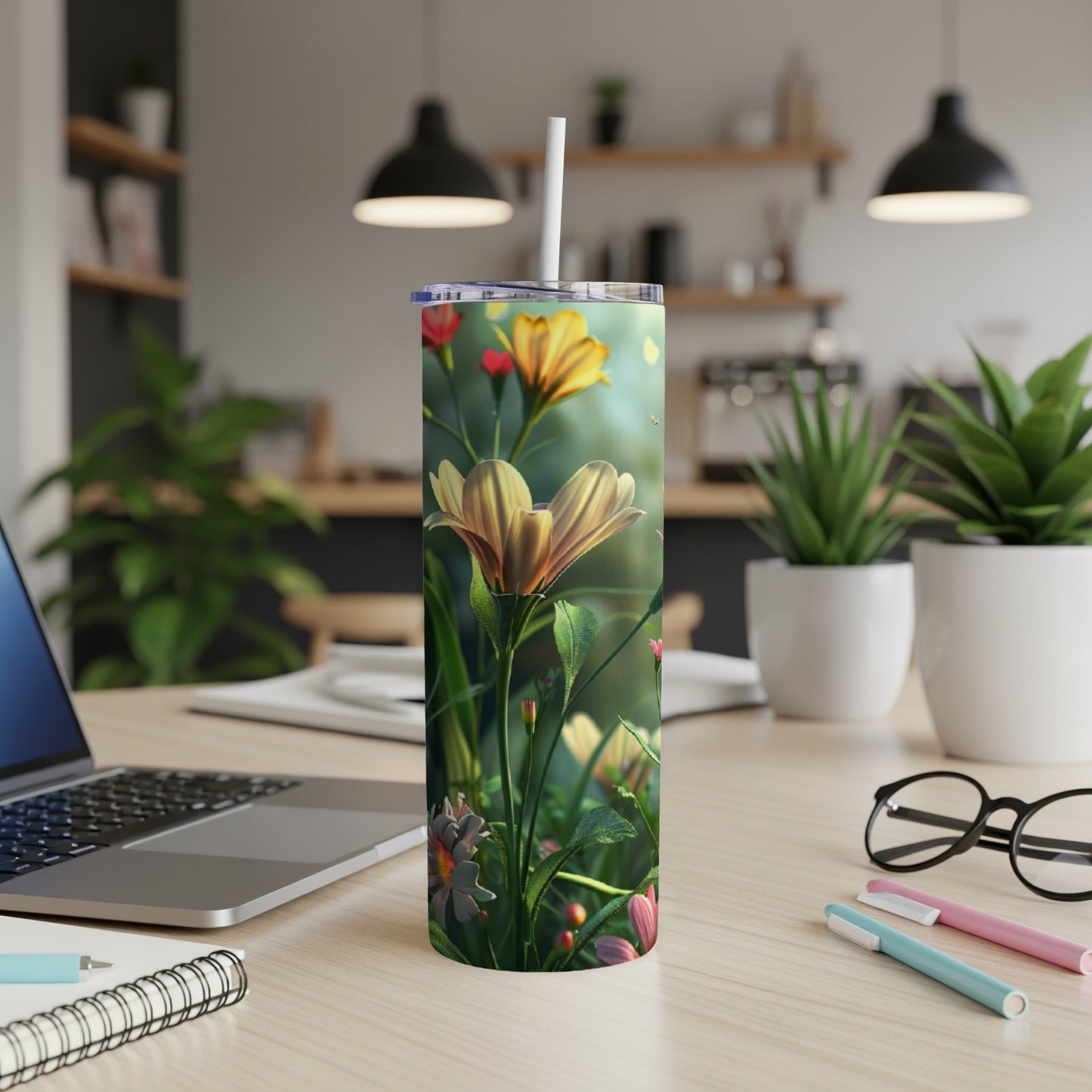 Yellow flower design on a tall, skinny tumbler on a desk with a laptop.