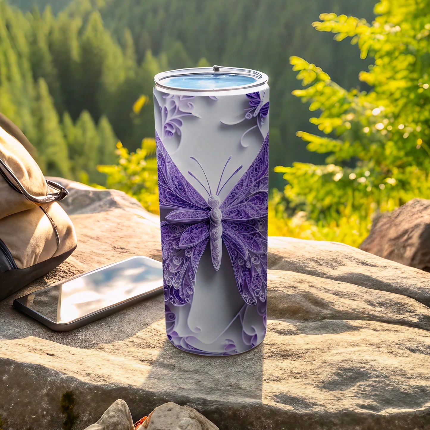 Purple butterfly tumbler on a rock with a backpack and phone.