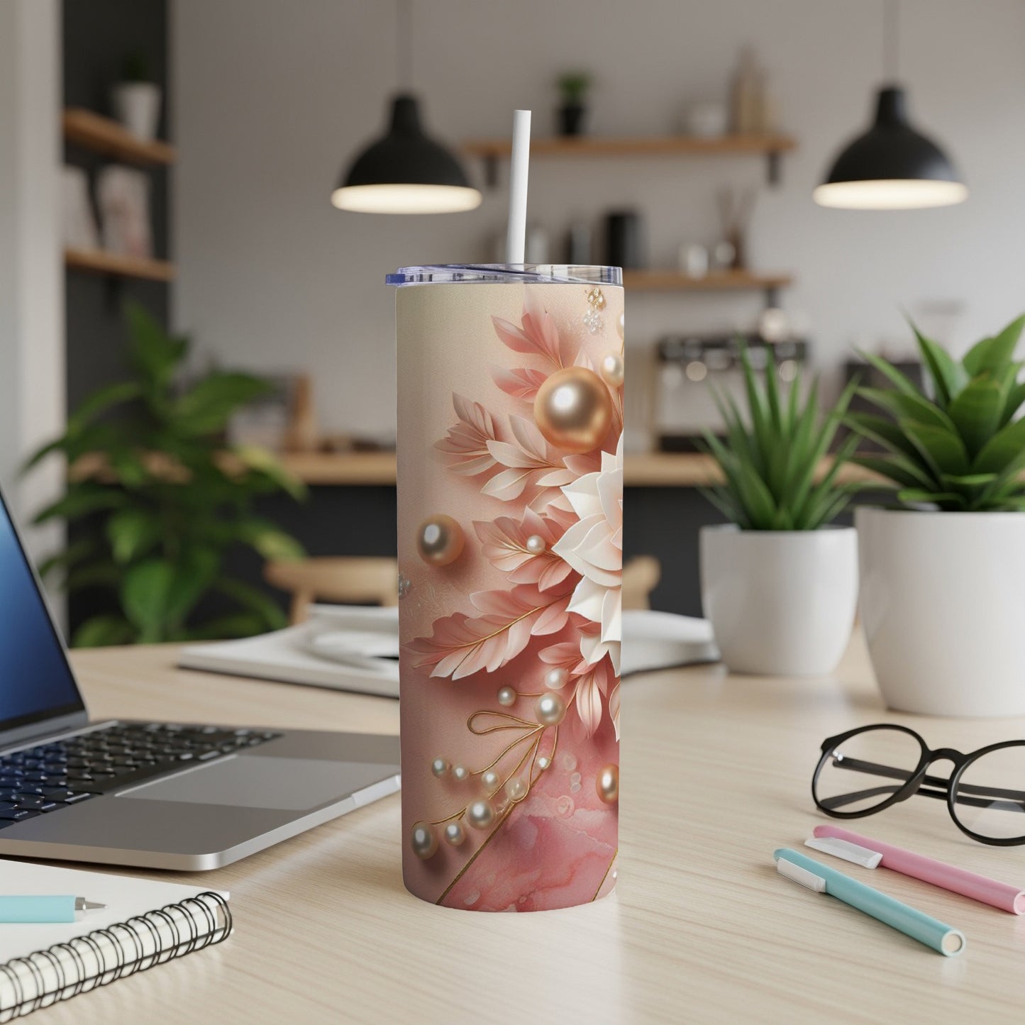 Pink floral patterned tumbler with pearls and a straw, on a desk.