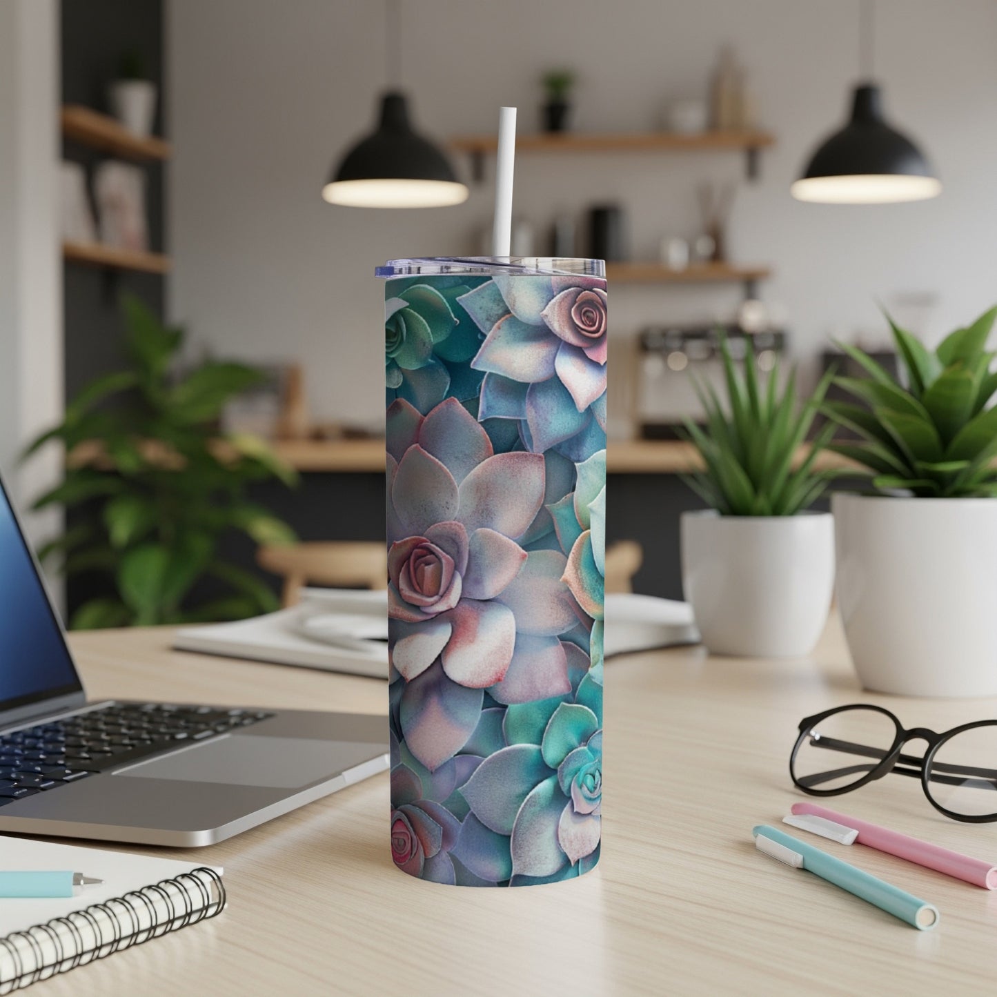 Succulent pattern on a white tumbler with a straw, on a desk.