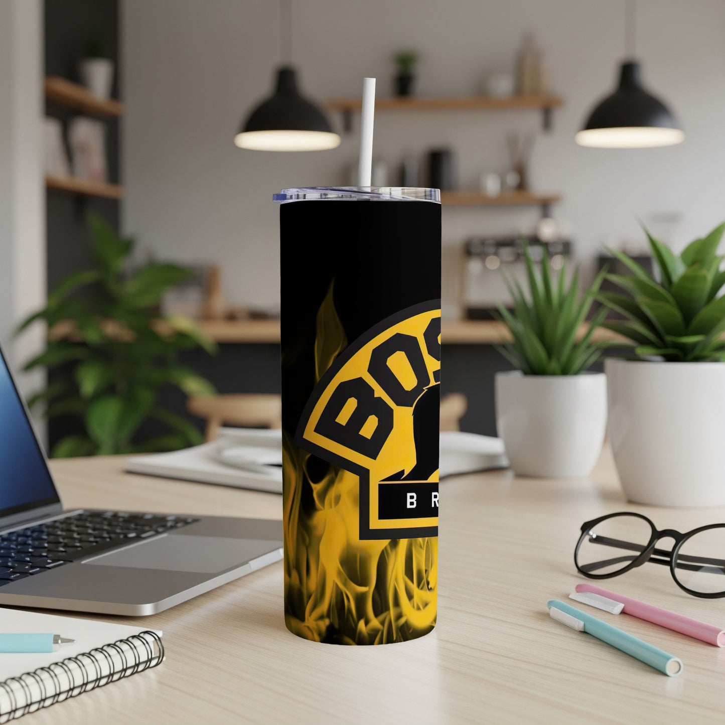 Black tumbler with yellow "BOSS" logo and flames, on a desk.