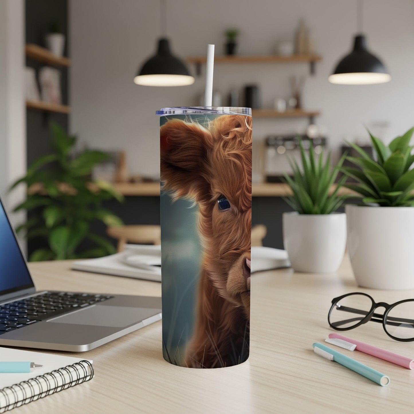 Fluffy Highland cow face on a tumbler with a straw and office desk background.