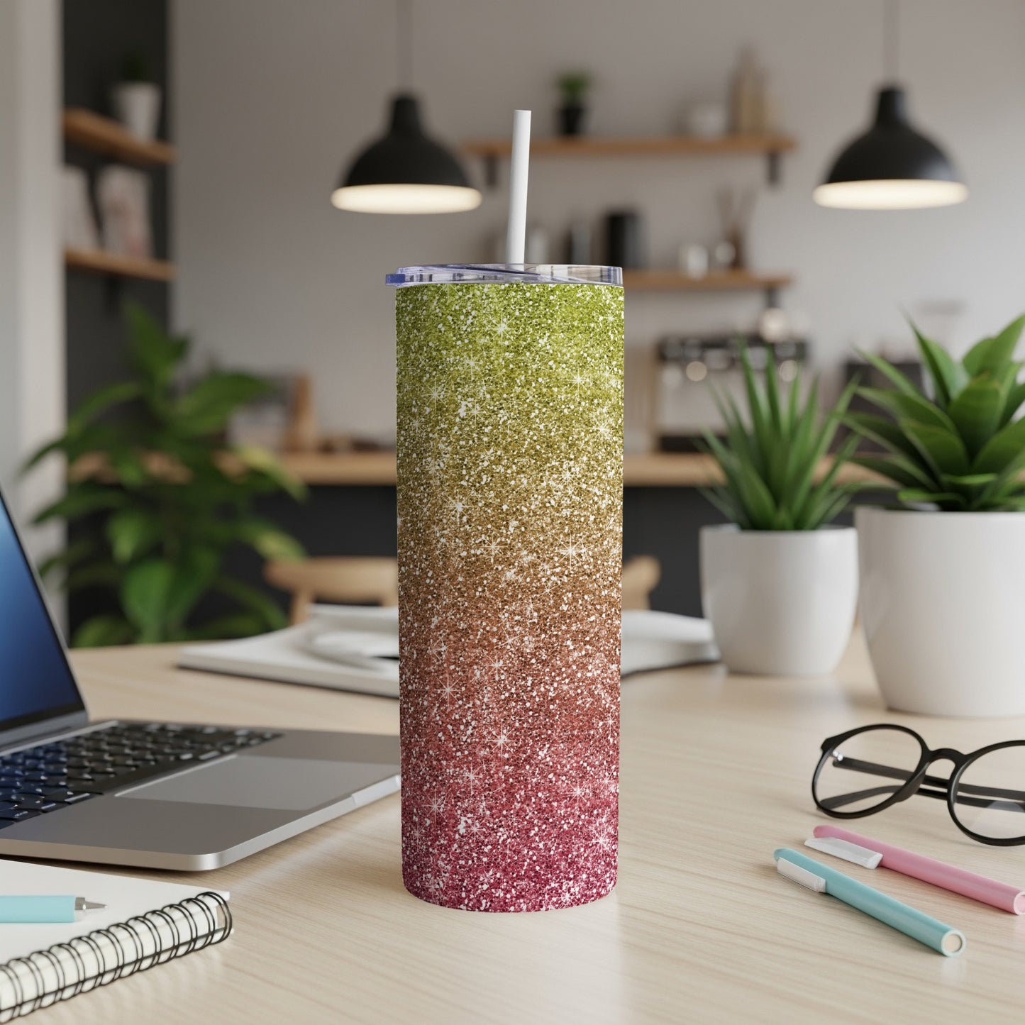 Glitter gradient tumbler with straw on a wooden desk.