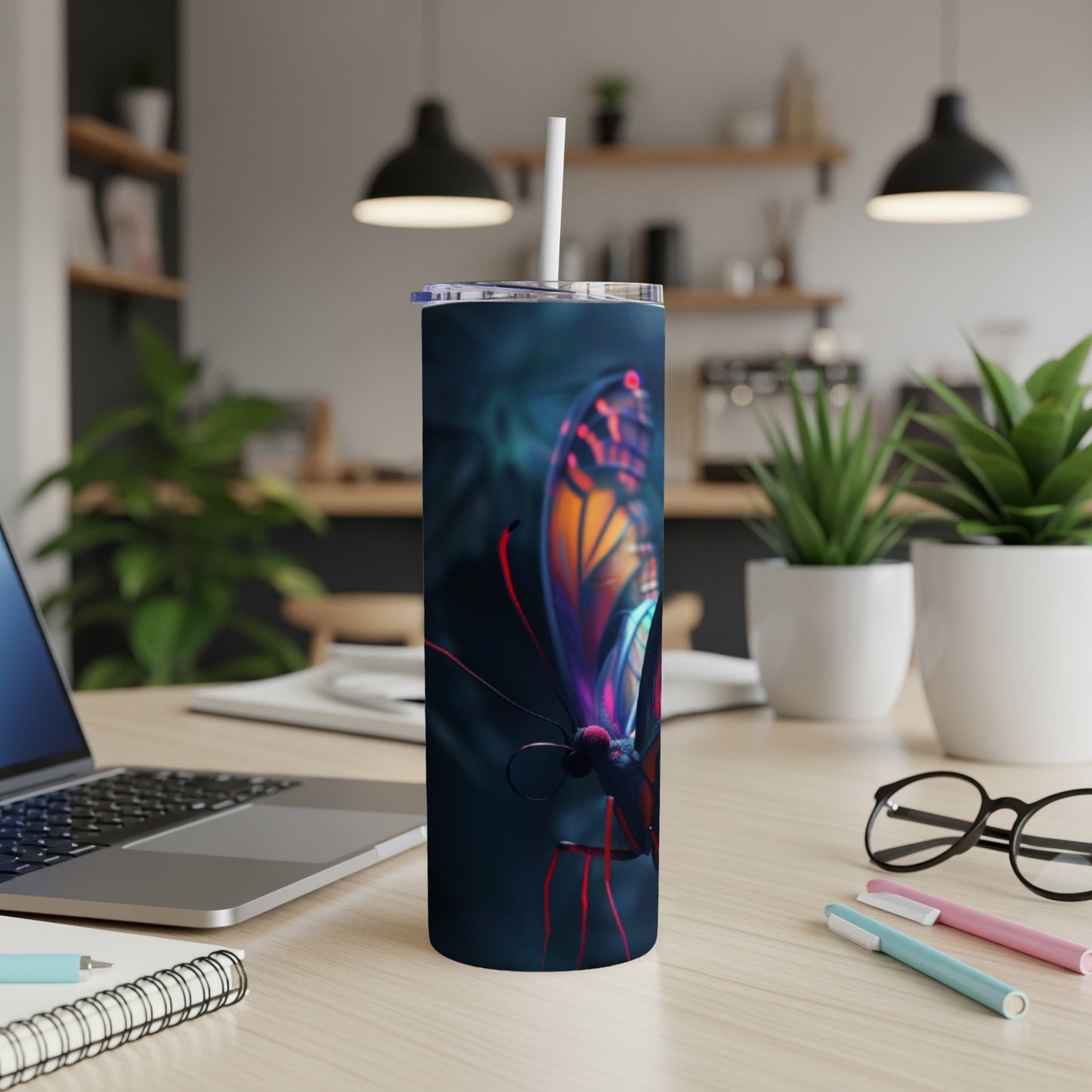 Dark tumbler with vibrant butterfly design and straw on a desk.