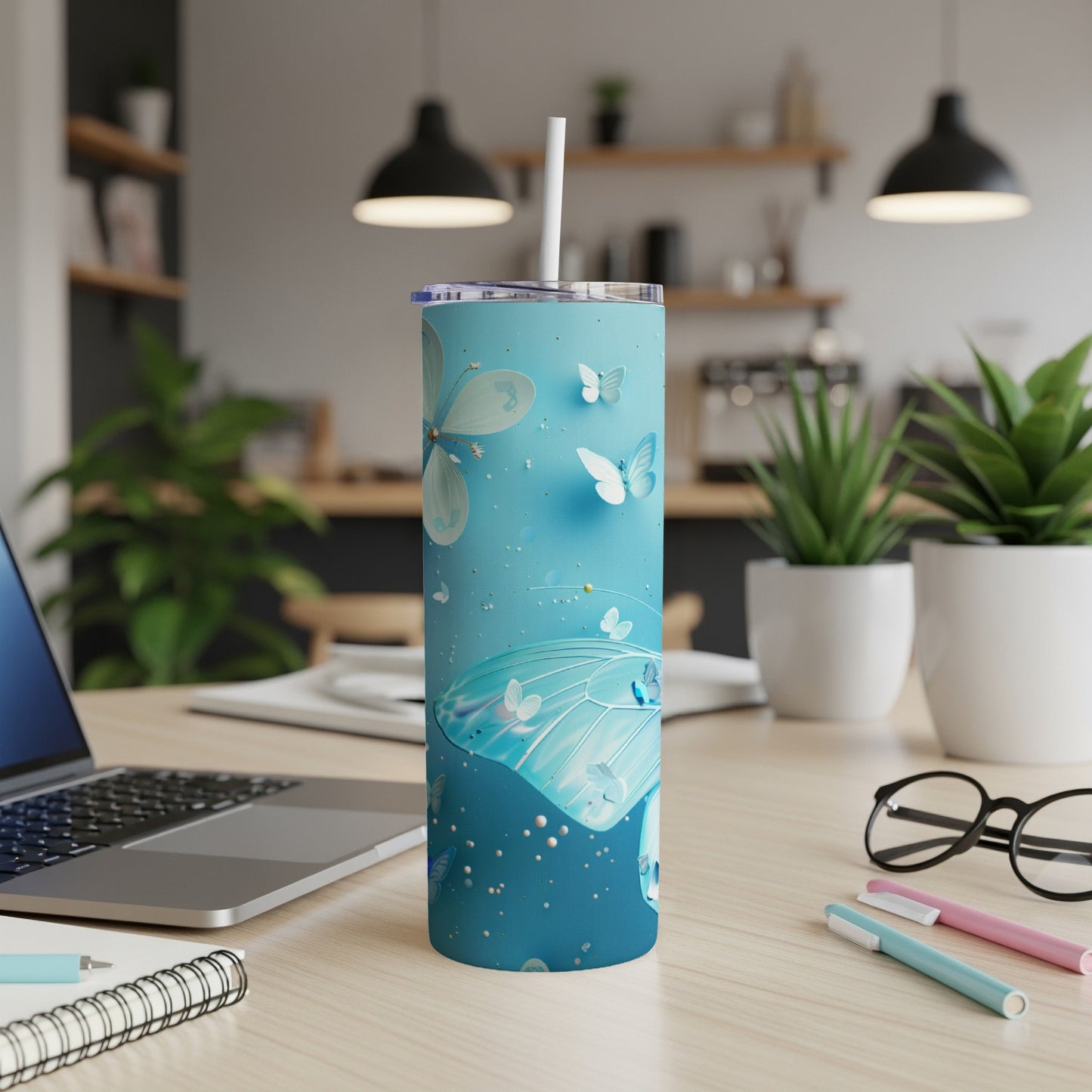 Blue tumbler with butterflies and a straw on a desk.