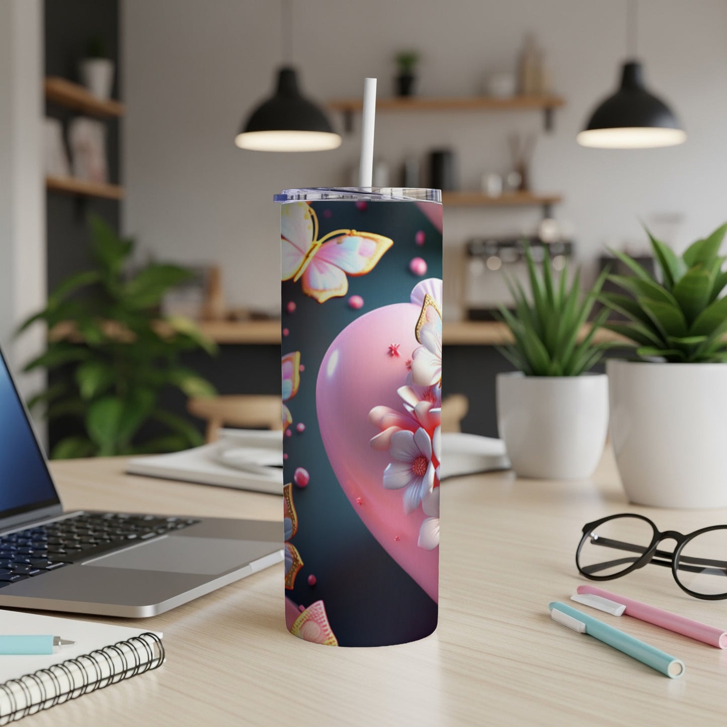 Pink heart tumbler with butterflies and flowers, sitting on a desk.