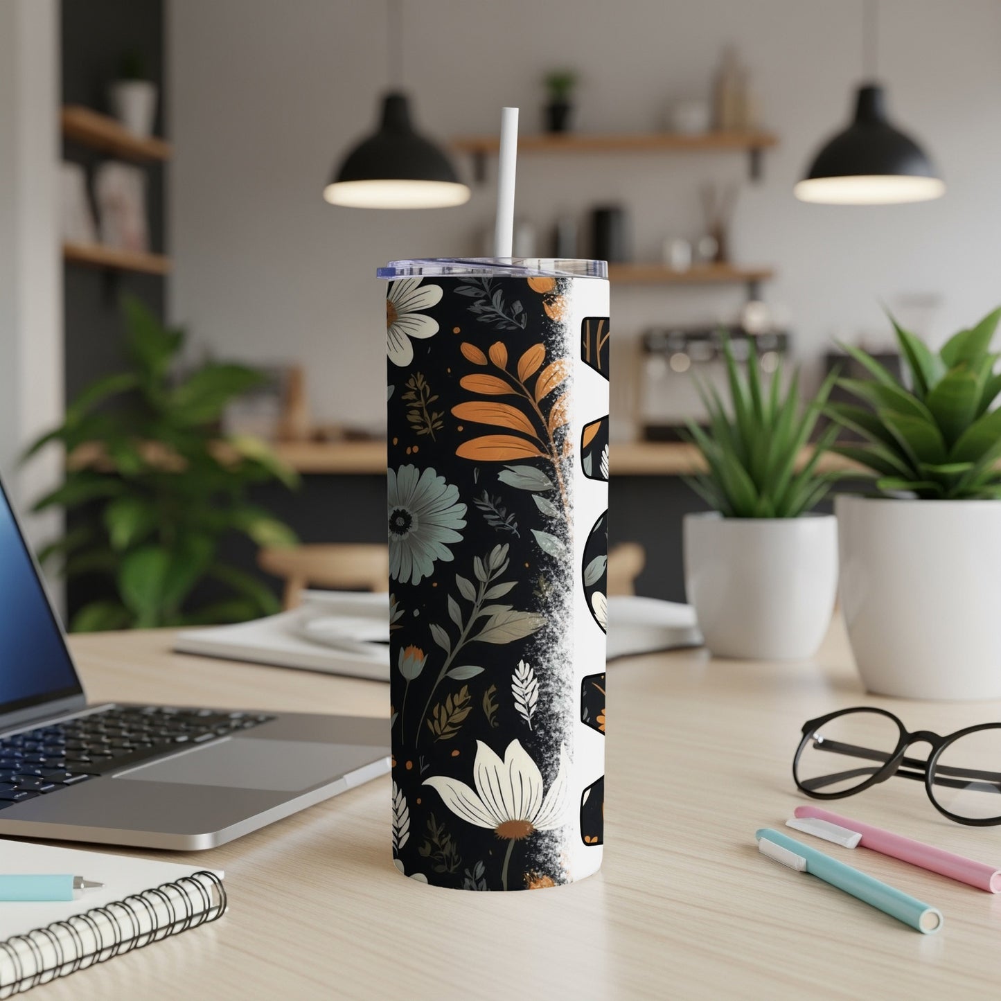 Floral and skull pattern tumbler with a straw on a wooden desk.