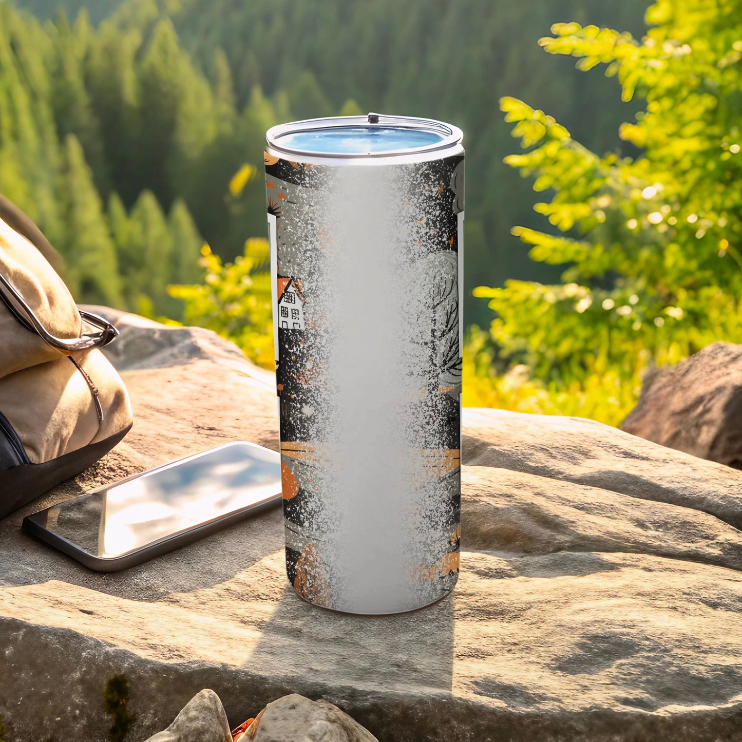 Tall tumbler with Halloween-themed design, resting on rocks outdoors.