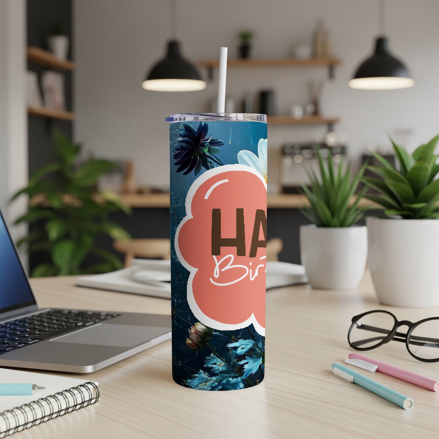 Happy Birthday tumbler with floral design on a desk.