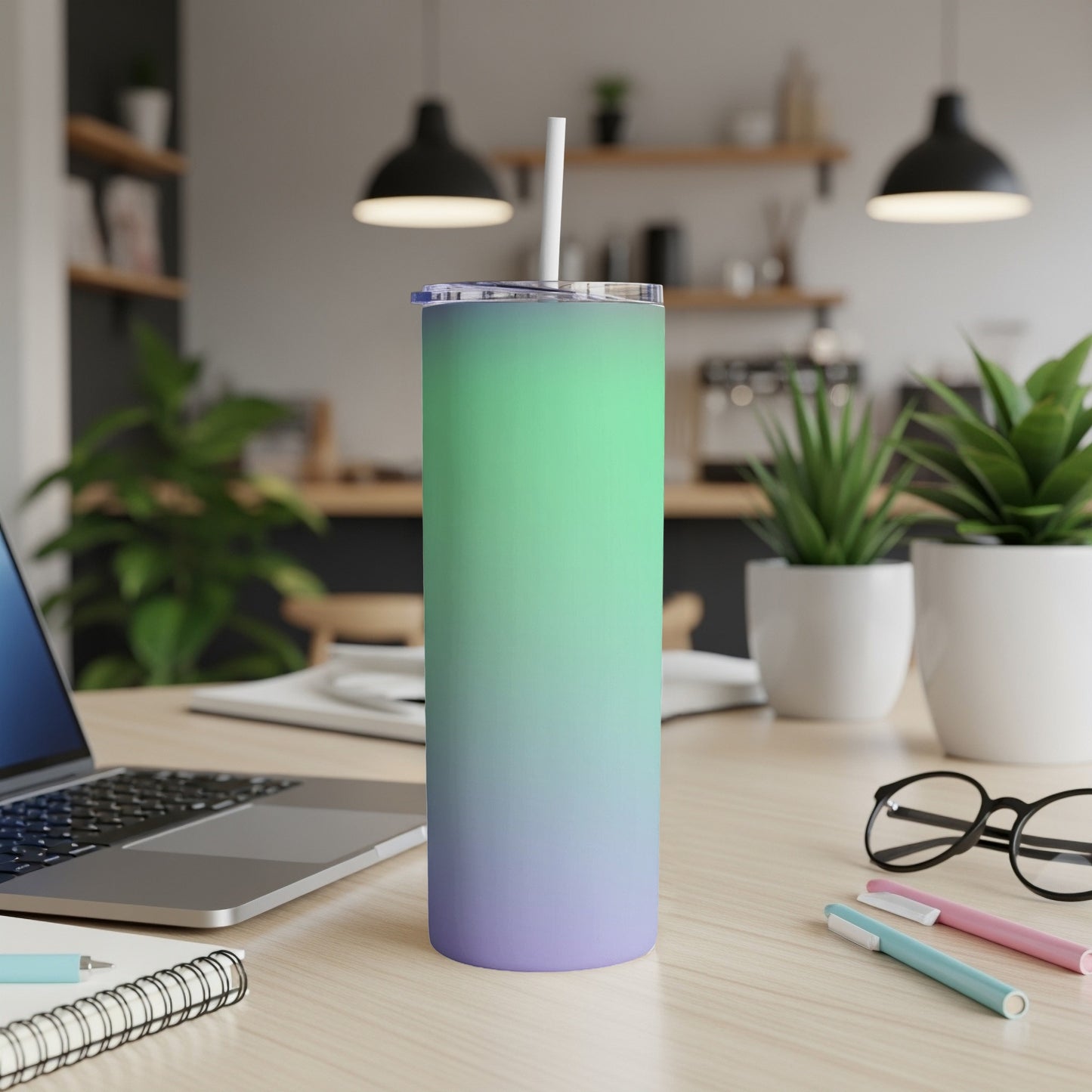 Green to purple gradient skinny tumbler with a straw on a desk.
