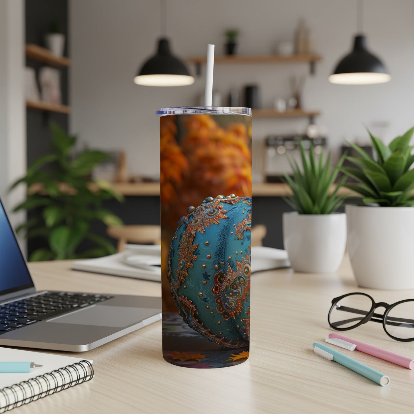 Turquoise ornament with ornate gold pattern on desk with laptop and pens.