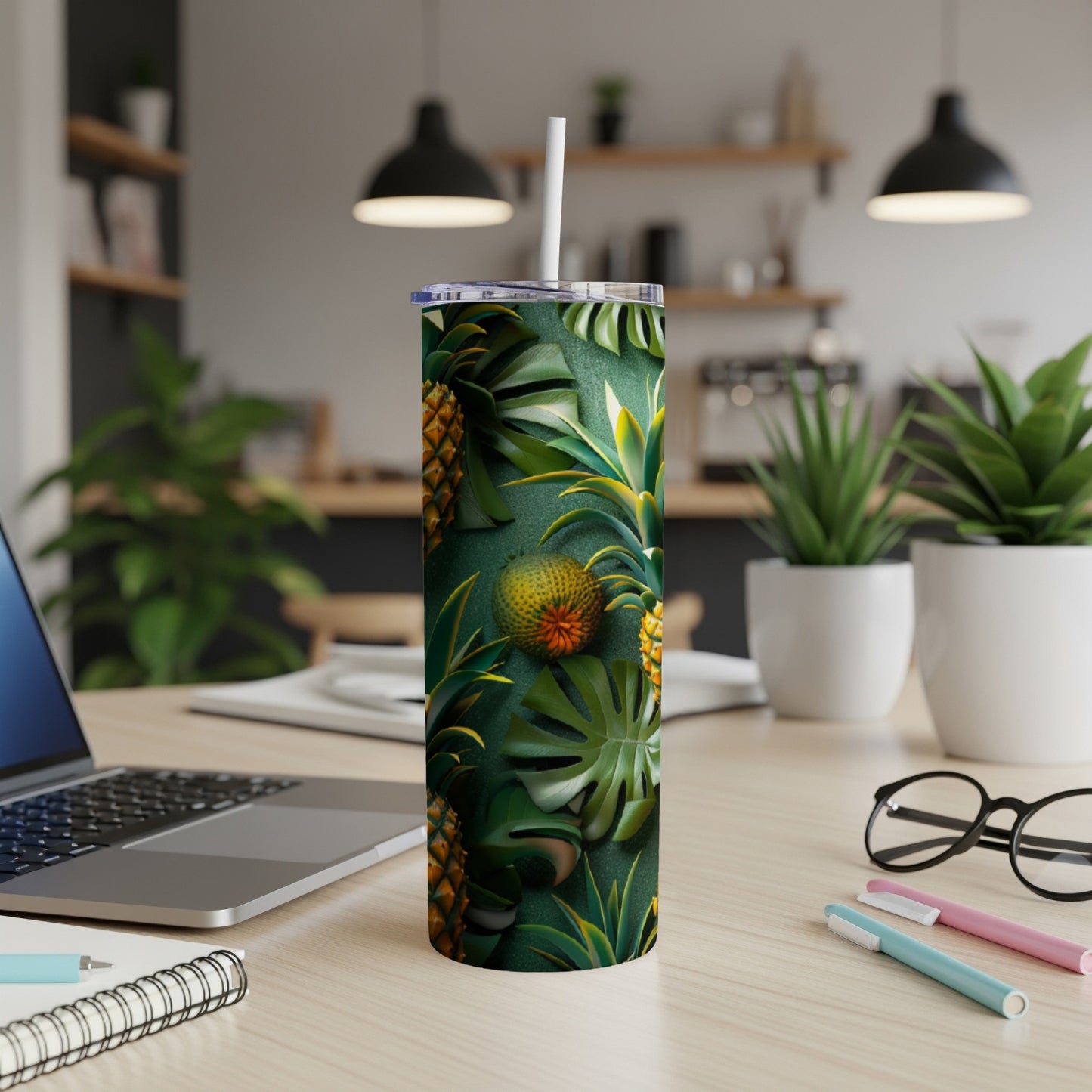 Green tumbler with pineapple and palm leaf pattern on a desk.