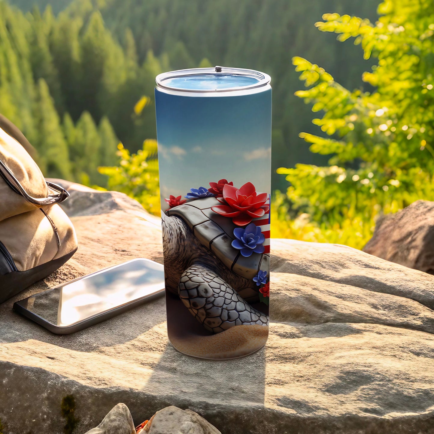 Turtle tumbler with floral and flag accents, next to phone and bag.