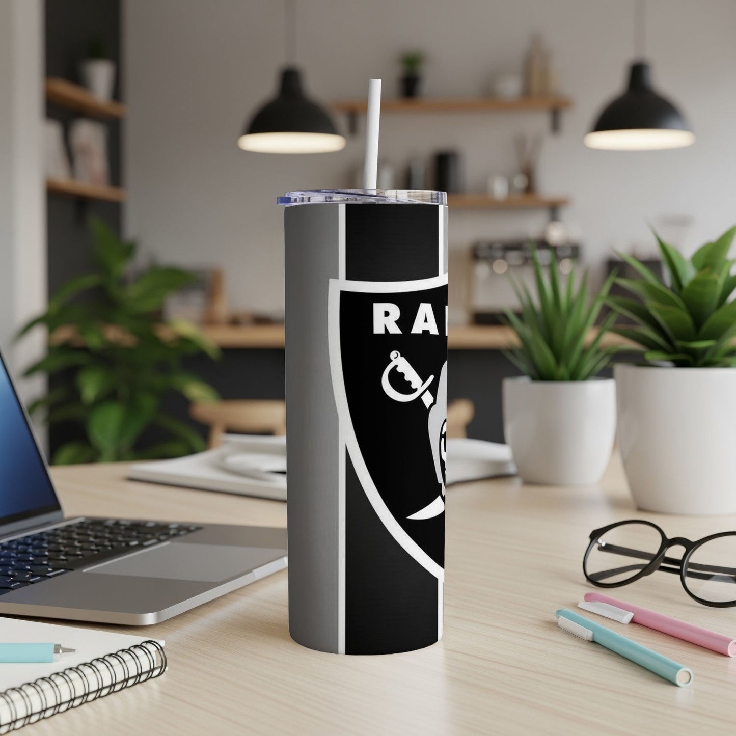 Las Vegas Raiders logo tumbler with straw on a wooden desk.