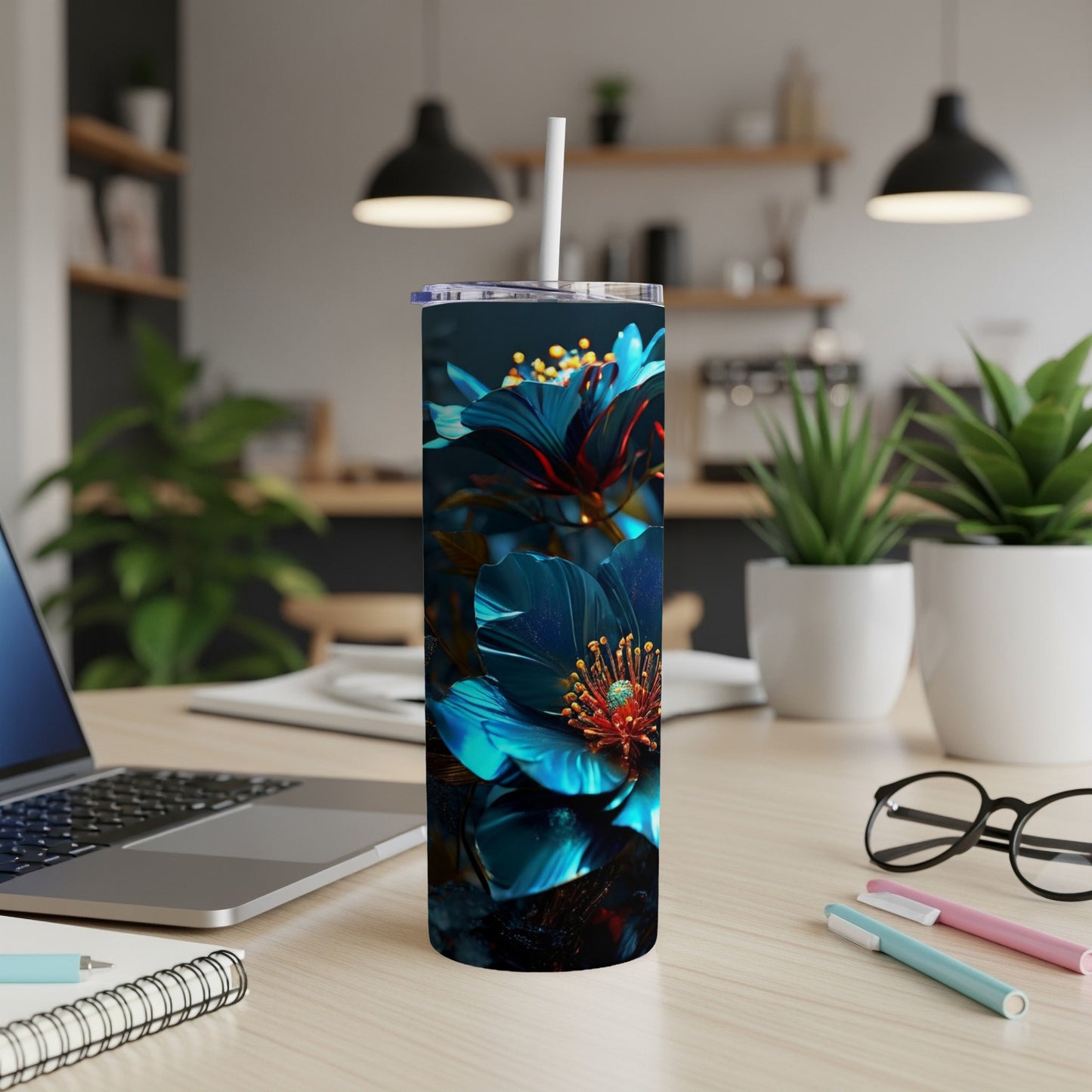Blue flower design on a tumbler with a straw on a desk.