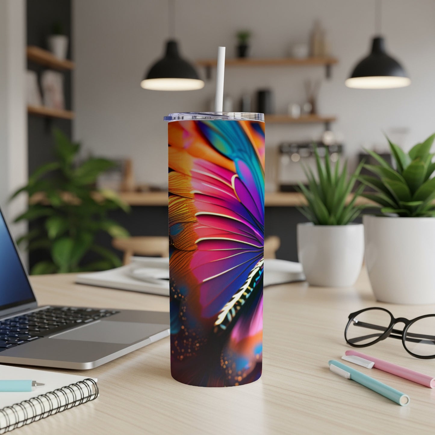 Colorful feather pattern on a tumbler with straw on a desk.