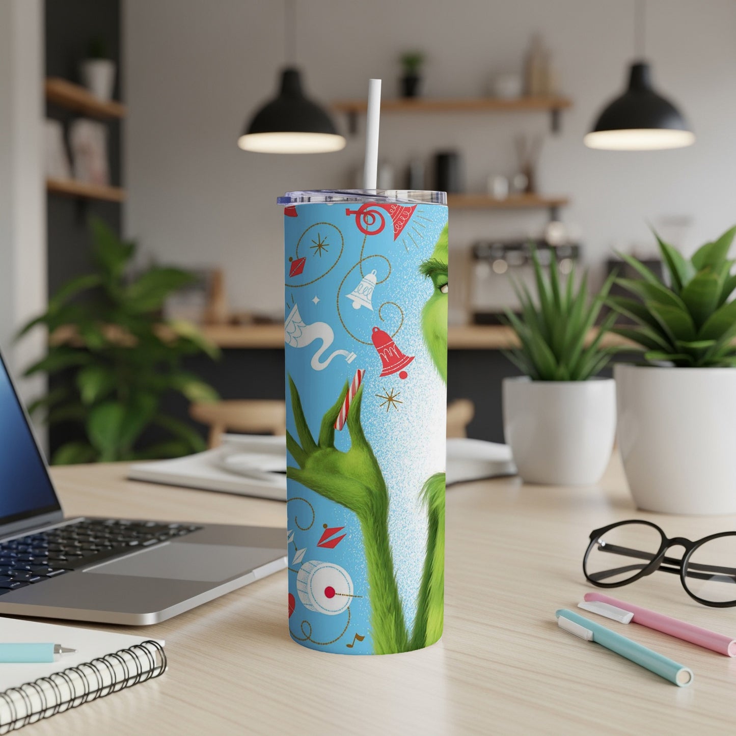 Grinch-themed tumbler with festive holiday icons on a desk.