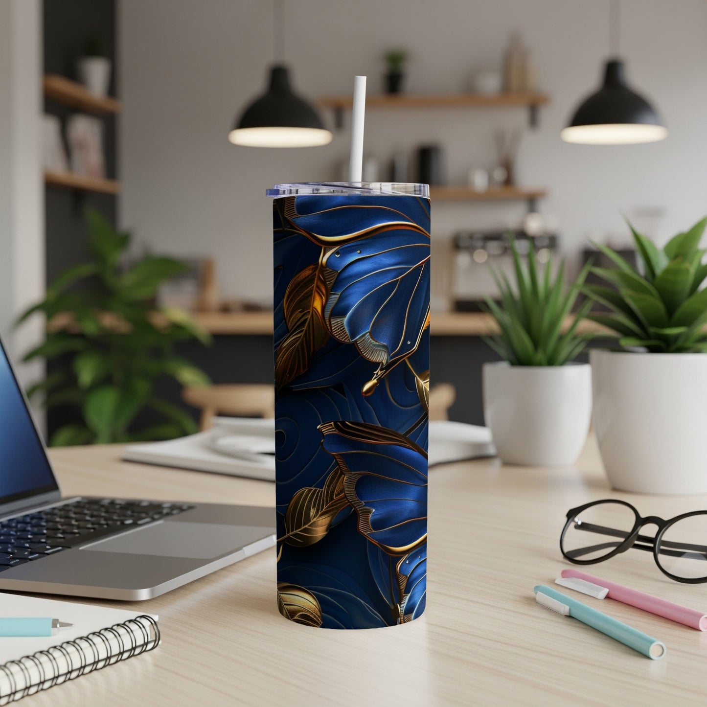 Blue and gold butterfly tumbler with straw on a desk.