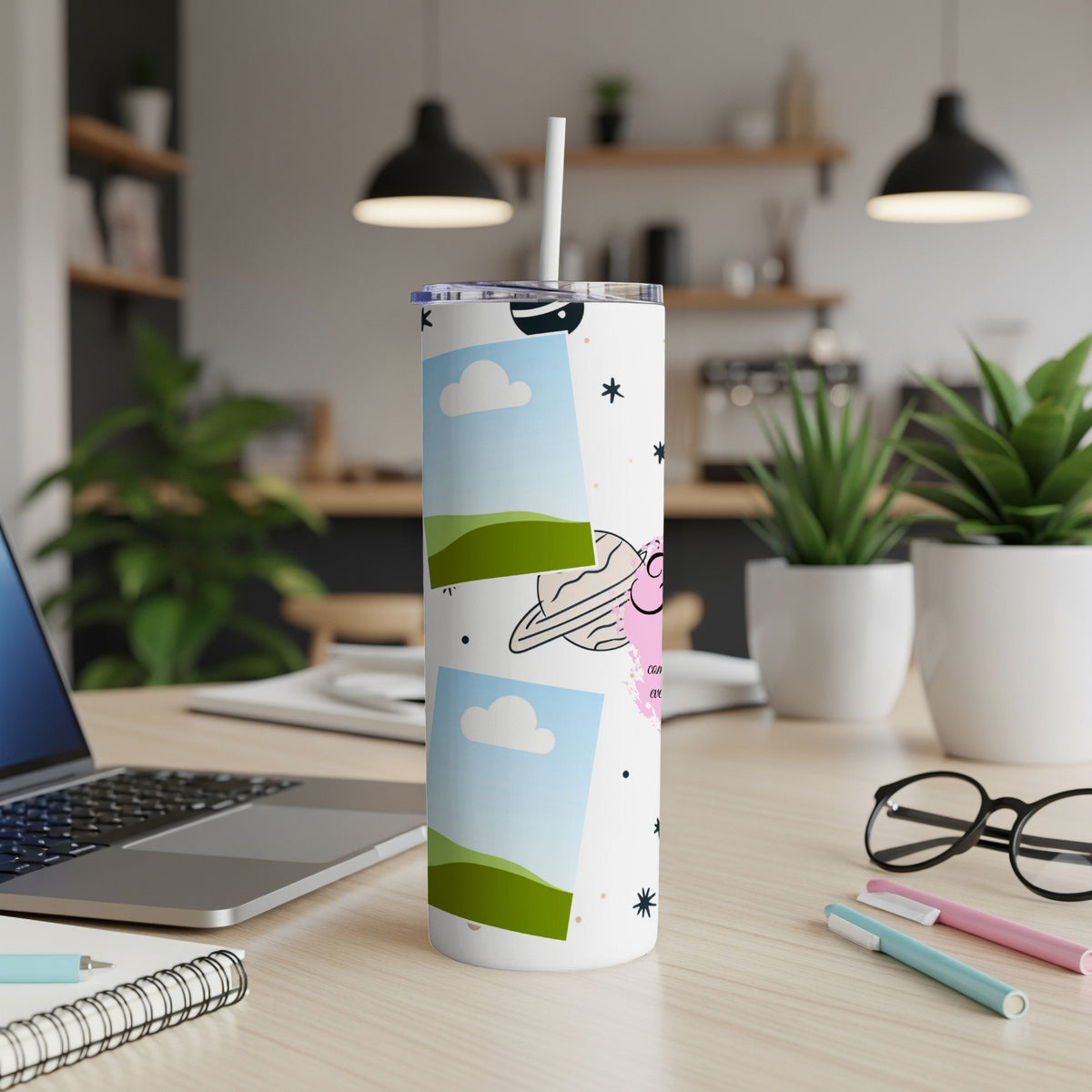White tumbler with cartoon planet and cloud designs, straw inserted.